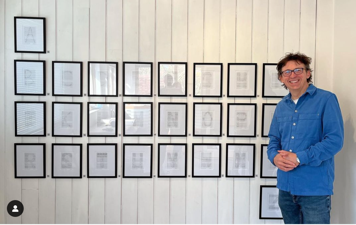 Will Todd in front of a row of framed letters from the Symphony of Letters